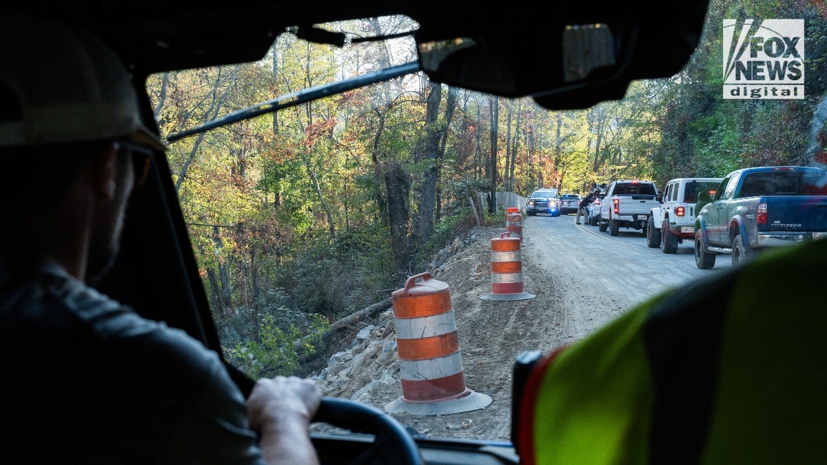 Jesse Craig drives by the shoulder of a paved road that was washed away during Hurricane Helene